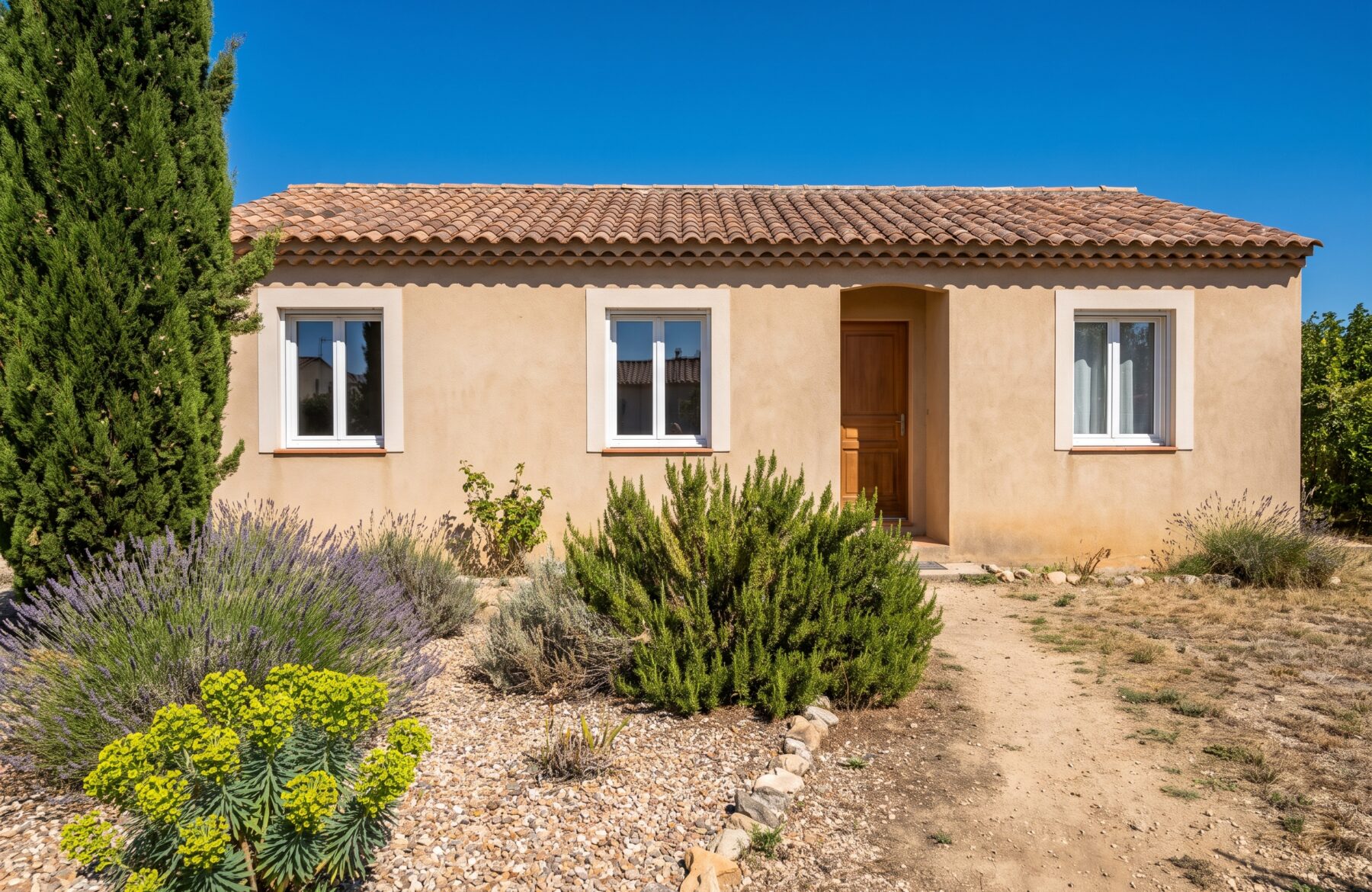 Maison de plain-pied dans l’Hérault équipée de fenêtres PVC blanches, façade crépie et jardin méditerranéen